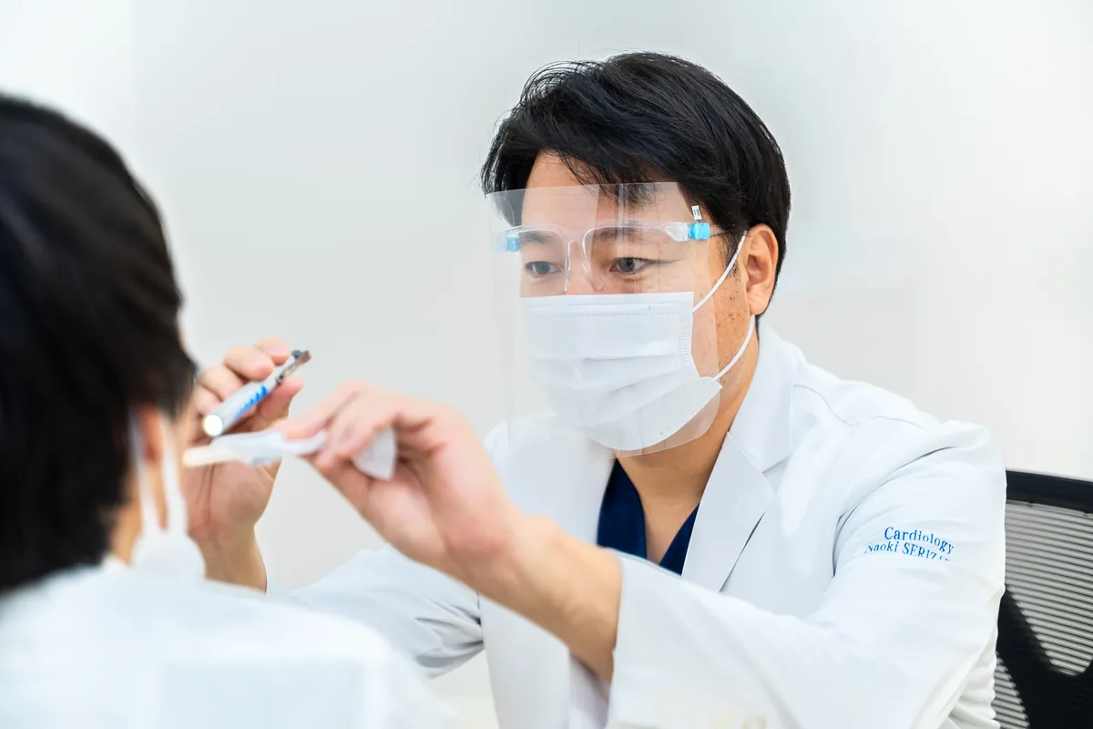 フェイスシールドを着けて、のど・感染症の診察を行う医師